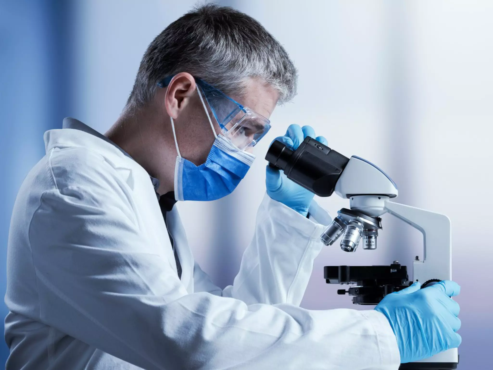 Mann in einer Laborumgebung schaut durch ein Mikroskop als Sinnbild für die wissenschaftlich untersuche Wirkung von Coffein