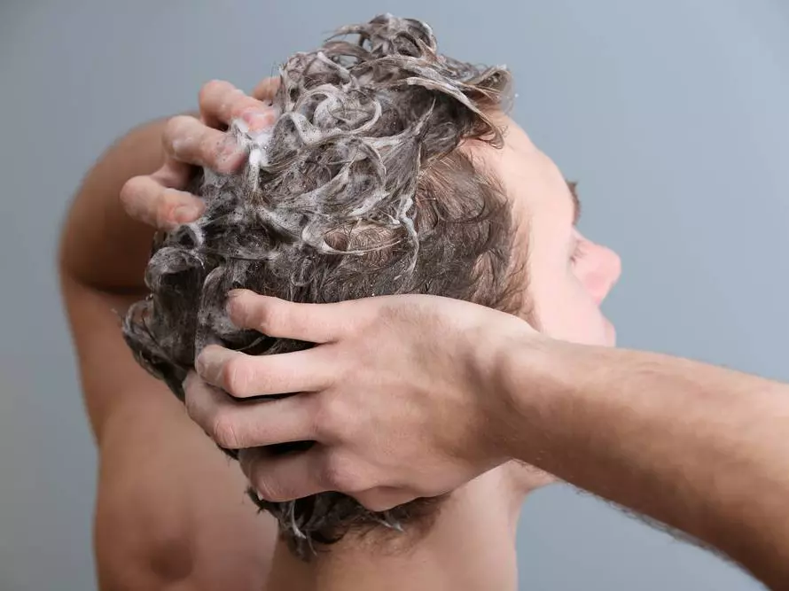Rückansicht von einem Mann, der sich die Haare wäscht als Sinnbild für das richtige Shampoo je nach Schuppenart