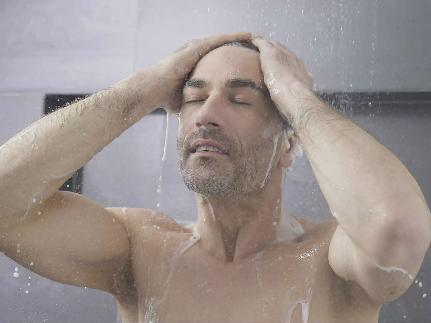 Ein Mann steht unter der Dusche und wäscht sich die Haare