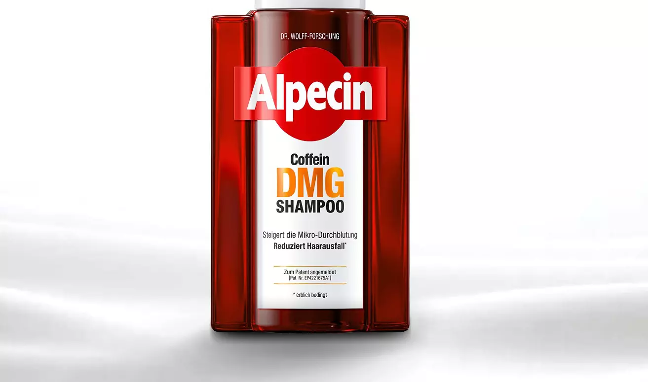 Eine rote Shampooflasche mit der Aufschrift "Alpecin Caffeine DMG Wirkkomplex" steht auf einer glatten, weißen Oberfläche.